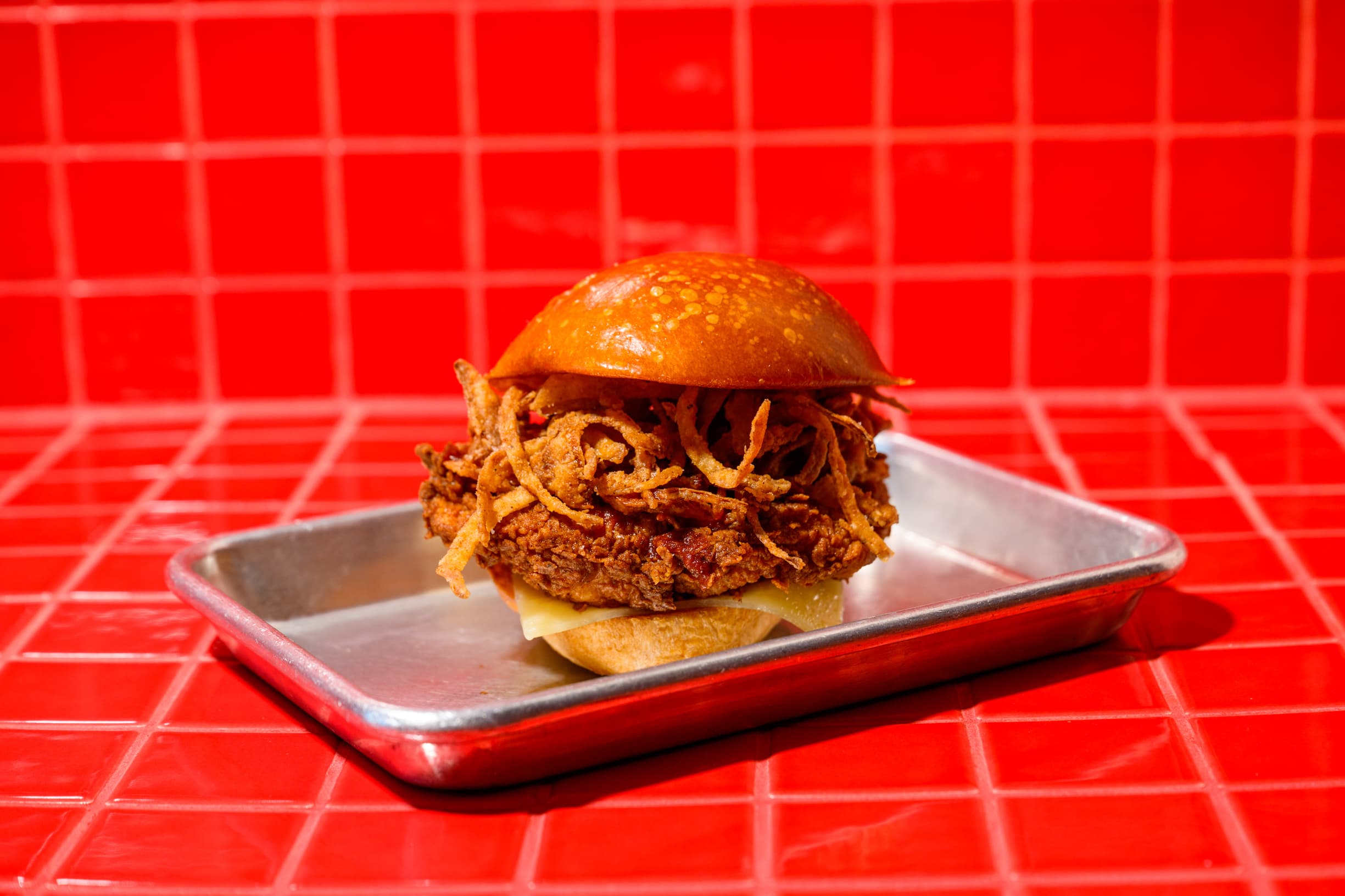 Fried chicken sandwich served alongside a basket of onion rings