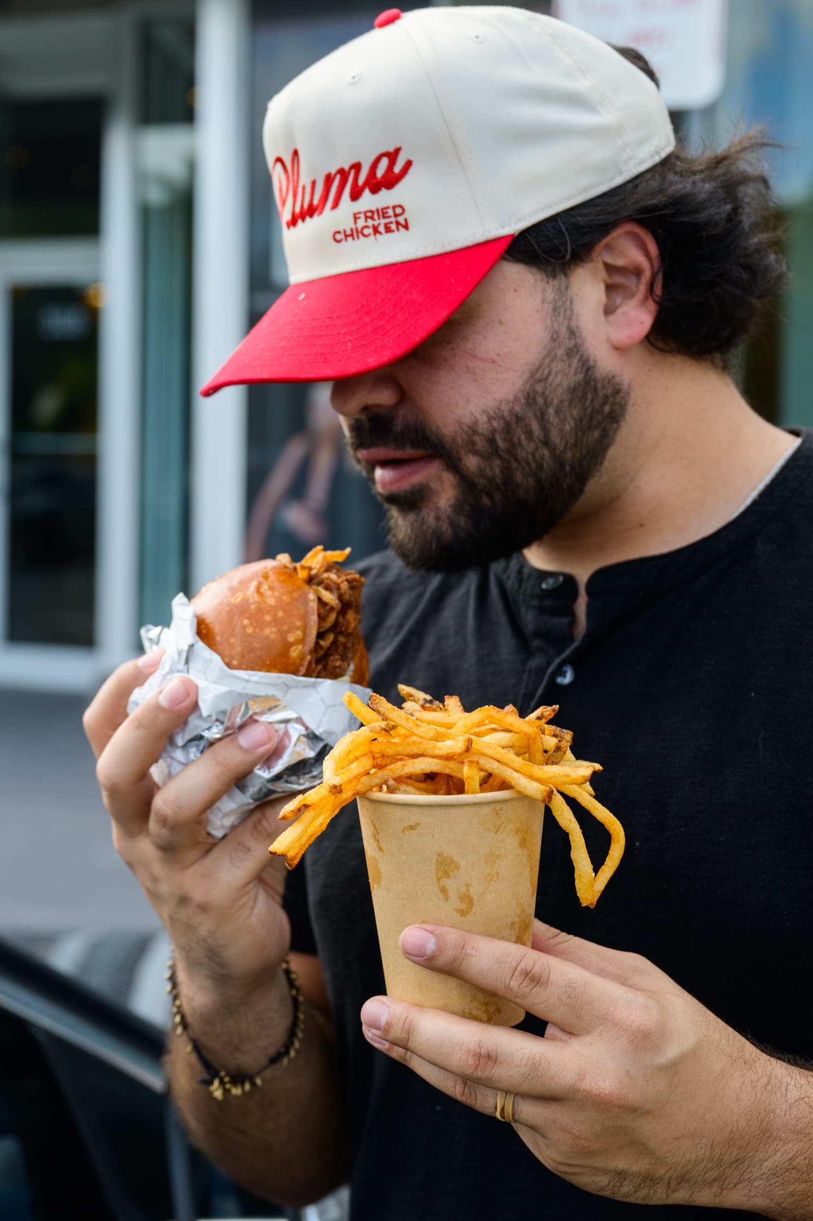 A guest about to take a bite of a fried chicken sandwich outside Pluma in Miami