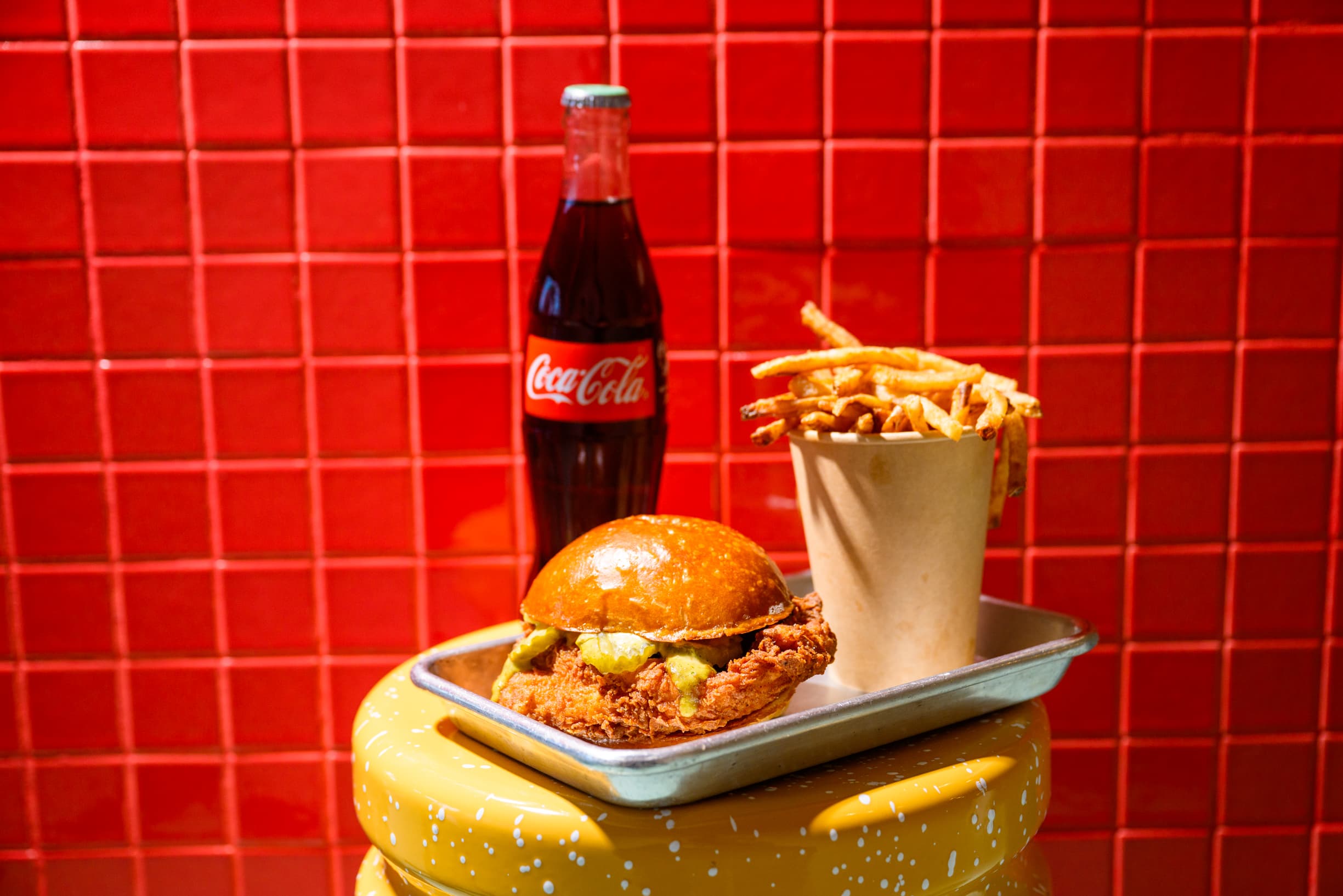 Pluma fried chicken sandwich next to an ice-cold Coca-Cola